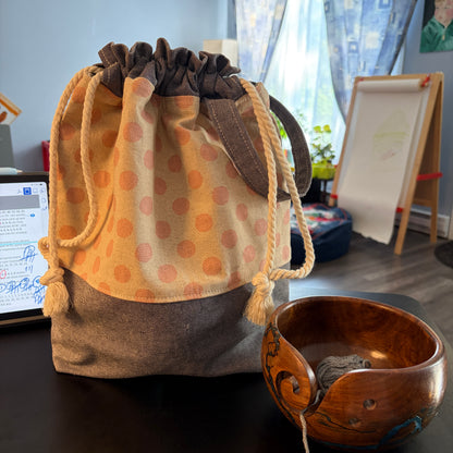 Pink polka-dot drawstring project bag with inner slip pockets and strap handle